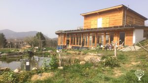 La maison avec sa serre aquaponique  et la mare au premier plan