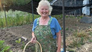 Judy in front of the Tulsi beds and greenhouse 
